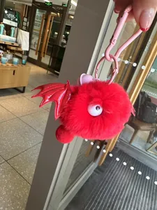 Macro-opname van rode pluche monster hanger met een groot oog en glanzende vleugels