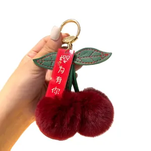 Plush cherry keychain with rex rabbit fur pom poms and green leather leaves on gold ring