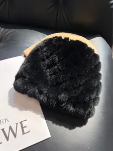 Detail of premium black faux fur hat showing dense plush texture on leather sofa background