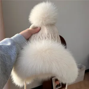 Dettaglio cappello in maglia a trecce con pompon in ecopelliccia e bordo in peluche