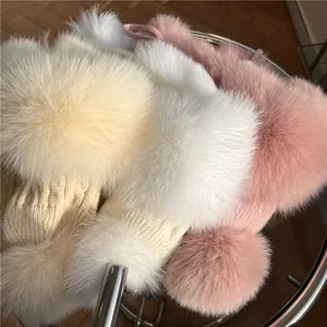 Tre cappelli in maglia con pompon soffici in beige, bianco e rosa in primo piano