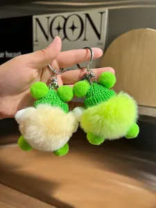 Détail de porte-clés en peluche mignons avec bonnets en tricot vert tenus en main