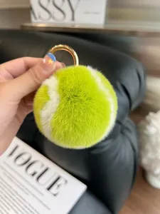 Close-up of fluffy neon green rabbit fur tennis ball keychain with gold ring buckle