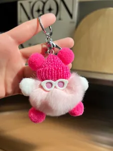 Détail du porte-clés en peluche rose avec bonnet en tricot rouge et lunettes de soleil