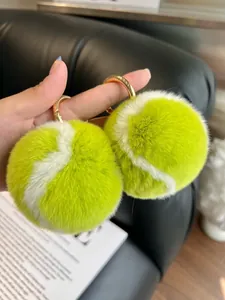 Detail of neon yellow plush tennis ball keychain with soft fur and gold metal ring