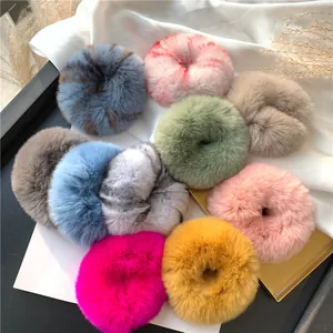 Detailed flat lay of colorful plush rabbit fur hair scrunchies on white fabric background