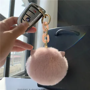 Pink faux rabbit fur cat ear keychain with acrylic chain and gold ring on a bag