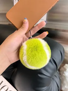 Detailed close-up of fluffy tennis ball keychain plush charm with yellow faux fur