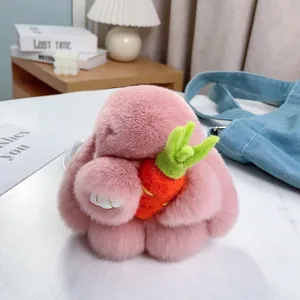 Porte-clés lapin en peluche rose avec une carotte posé sur une table en bois