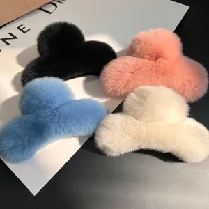 Detail of four fluffy faux rabbit fur hair claws in black, pink, blue and beige colors
