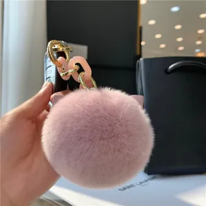 Detail of pink faux fur pompom keychain with cat ears and gold resin chain strap