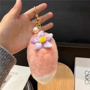 Detail of pink faux fur tail keychain with purple fabric flower and golden hardware