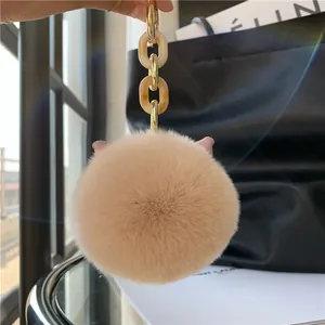 Detail of plush cat ear keychain with golden amber resin chain on a black bag