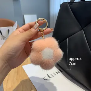 Porte-clés fleur en peluche rose avec anneau doré sur un sac en cuir noir