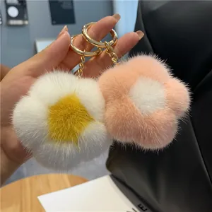 Vue détaillée de porte-clés fleurs en peluche blanc et rose avec anneau doré brillant