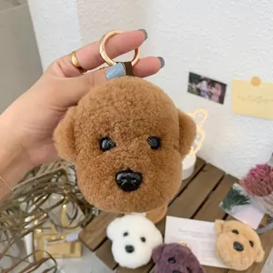 Detail of plush teddy dog keychains in brown, white, purple and khaki with gold rings