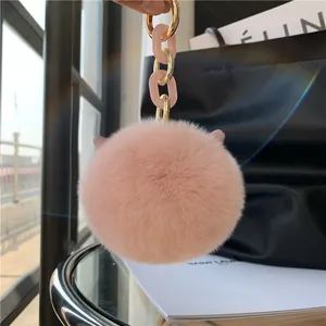 Close-up of fluffy pink faux fur ball keychain with elegant gold and pink resin chain link