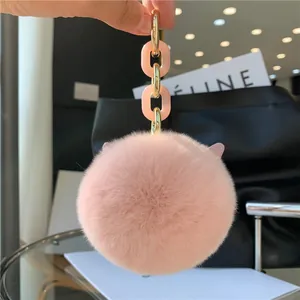 Detail of pink fluffy faux rabbit fur keychain hanging on a black leather bag