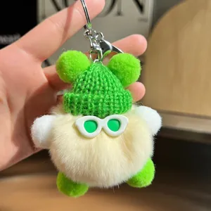 Porte-clés peluche jaune avec bonnet vert et lunettes, tenu dans la main