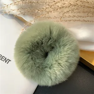 Close-up of fluffy sage green rabbit fur hair scrunchie on a decorative vintage tray