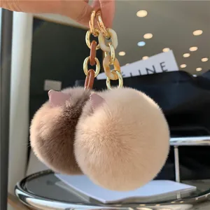 Close-up of fluffy cat ear fur pompom keychains in brown and beige with gold metal rings