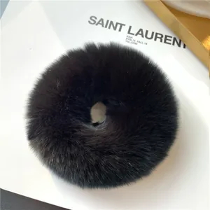 Detailed view of a soft black rabbit fur scrunchie on a minimalist white background