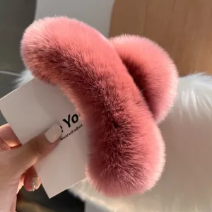 Close-up of a large coral pink plush faux fur hair claw clip held in hand for detail