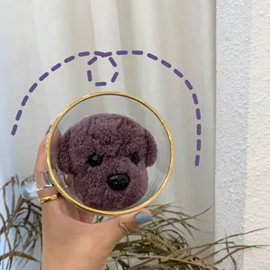 Detail of creative glass mug featuring a gold rim and cute purple plush teddy dog inside