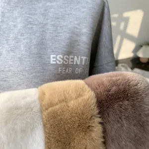 Close-up of plush faux fur scarves in white, apricot, and brown on a grey sweatshirt