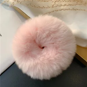 Close-up of soft pink rabbit fur scrunchie with fluffy texture on white silk background