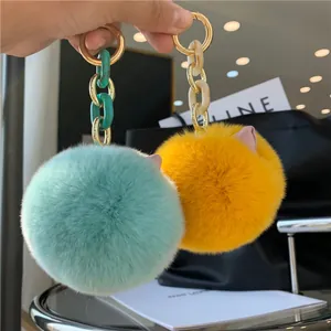 Close-up of fluffy rex rabbit fur cat ear keychains in mint green and ginger yellow