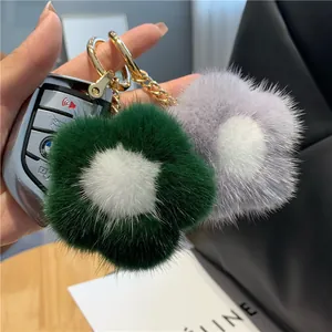 Détail de porte-clés fleurs en fourrure de vison vert et violet sur un sac à main