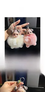 Detail of pink and white faux fur doll charms with silver keyrings on a bag