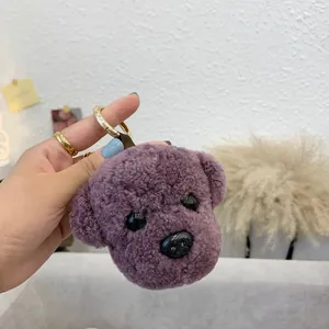 Close-up of purple plush teddy dog keychain with soft wool texture and golden metal ring