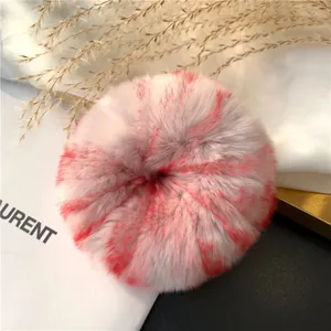 Detail of fluffy grey rex rabbit fur scrunchie with red marble texture on chic setup
