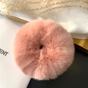 Detail of soft pink faux rabbit fur scrunchie on decorative silk and gold tray
