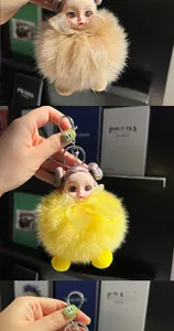 Detail of cute doll keychain with fluffy fur pompom, ribbon bow and silver metal clasp