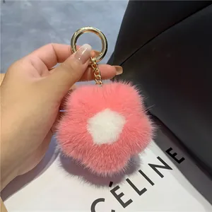 Détail d'un porte-clés fleur en fourrure de vison avec anneau doré sur sac en cuir noir