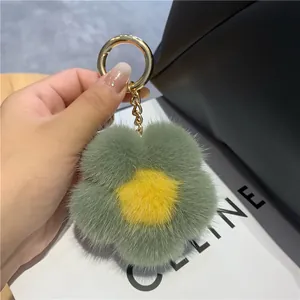 Détail du porte-clés fleur en peluche avec anneau doré sur un sac en cuir noir