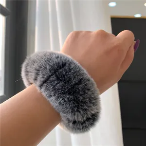 Fluffy rabbit fur scrunchie in grey-white worn on wrist, soft winter accessory style