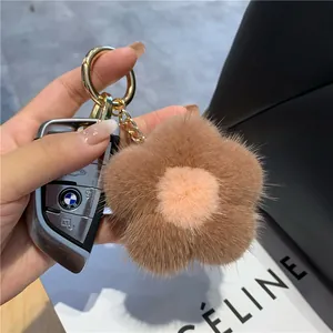 Gros plan d'un porte-clés fleur en fourrure de vison sur un sac à main en cuir noir