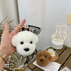 Close-up of fluffy white and brown teddy dog plush keychains with golden metal ring