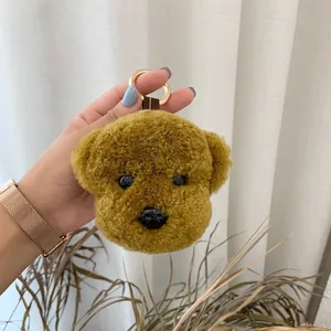 Detail of soft curly plush teddy dog keychain with golden metal ring and brown ribbon