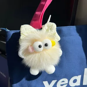 Schattige pluizige roetbal sleutelhanger met strik op een blauwe canvas tas