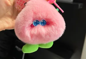 Close-up of pink fluffy monster keychain with blue starry eyes and peach princess tag