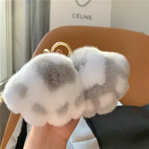 Close-up of soft grey and white faux fur cat paw keychain with a gold metal ring
