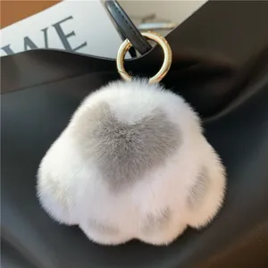 Detail of white faux fur heart keychain with gold metal ring on a black leather handbag