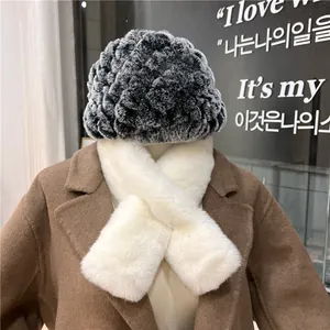 Dettaglio outfit invernale con cappello in finta pelliccia e sciarpa di peluche bianca
