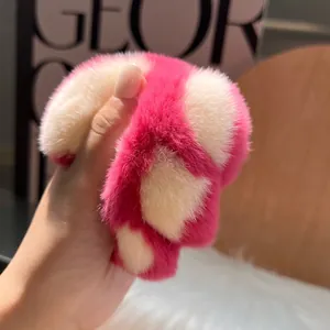 Rosa-beige kariertes Plüsch-Katzenpfoten-Haargummi vor einem warmen Wohn-Hintergrund