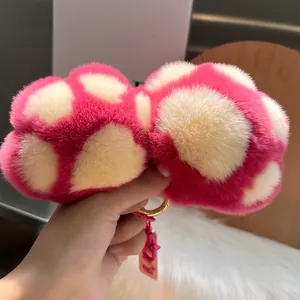 Nahaufnahme vom flauschigen rosa Katzenpfoten-Schlüsselanhänger aus weichem Kaninchenfell